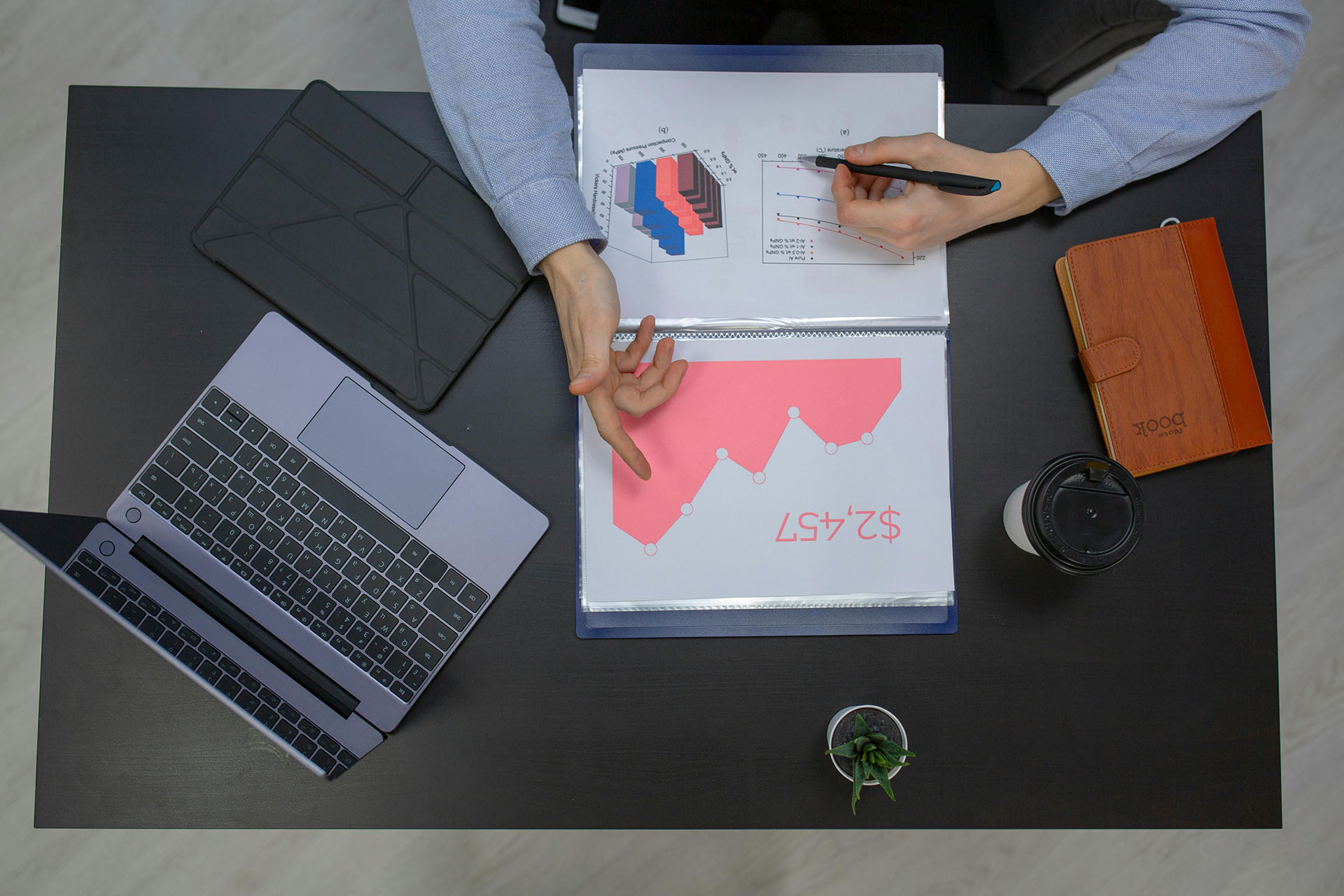 Person sitting at a desk with a laptop looking at charts