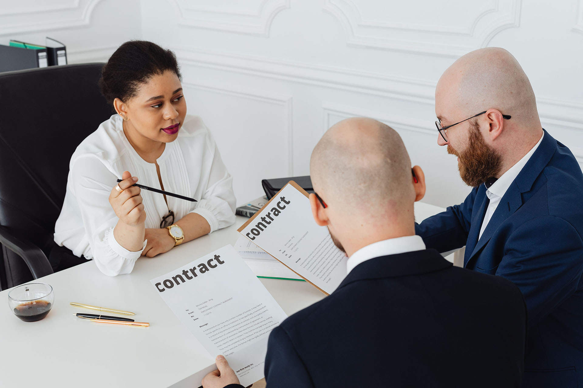 Two men and a woman looking at contracts