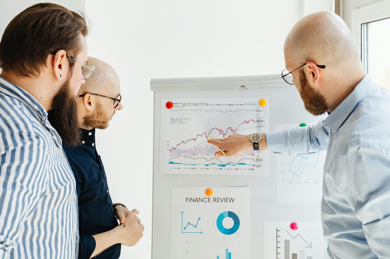 Three men looking a financial review charts