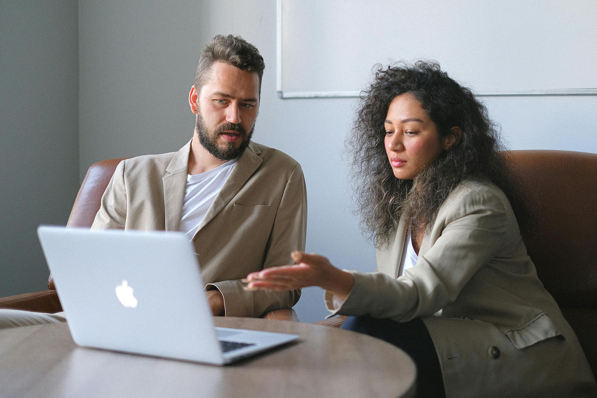 A man and a woman sitting at desk looking at an apple computer