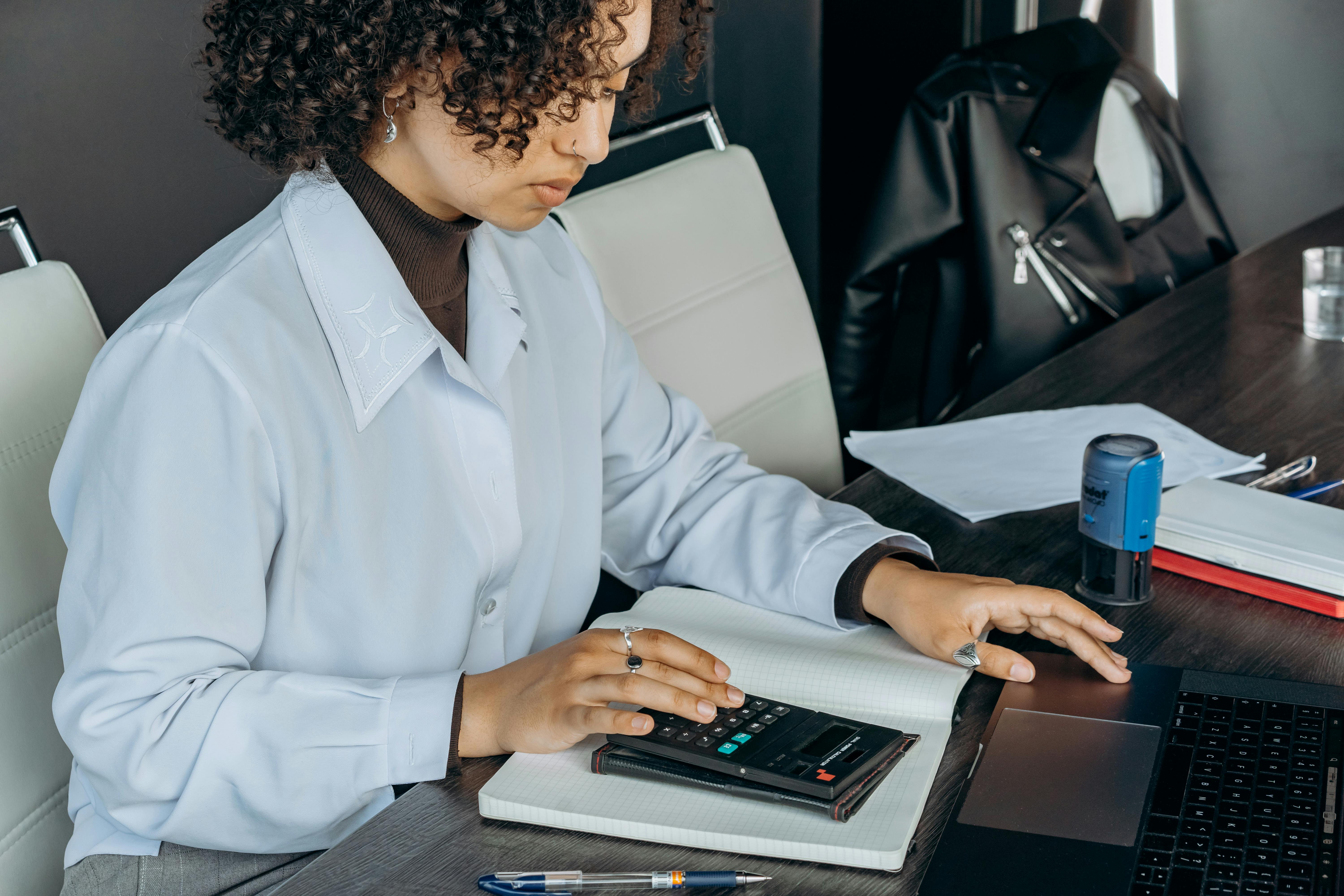 Woman in white jacket using a calculator