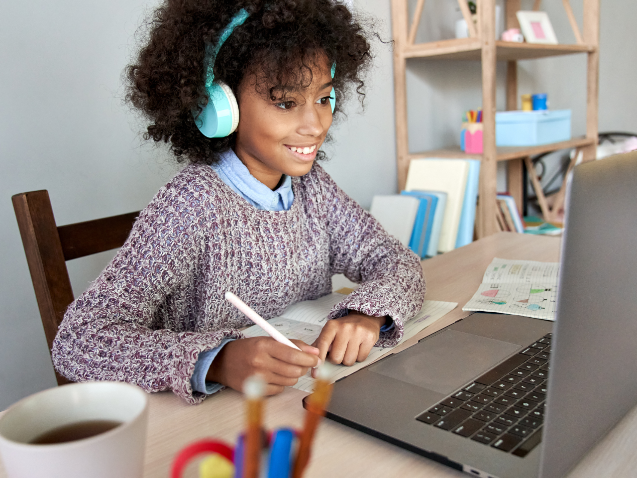 Young student with headphones engaged in study material on laptop.
