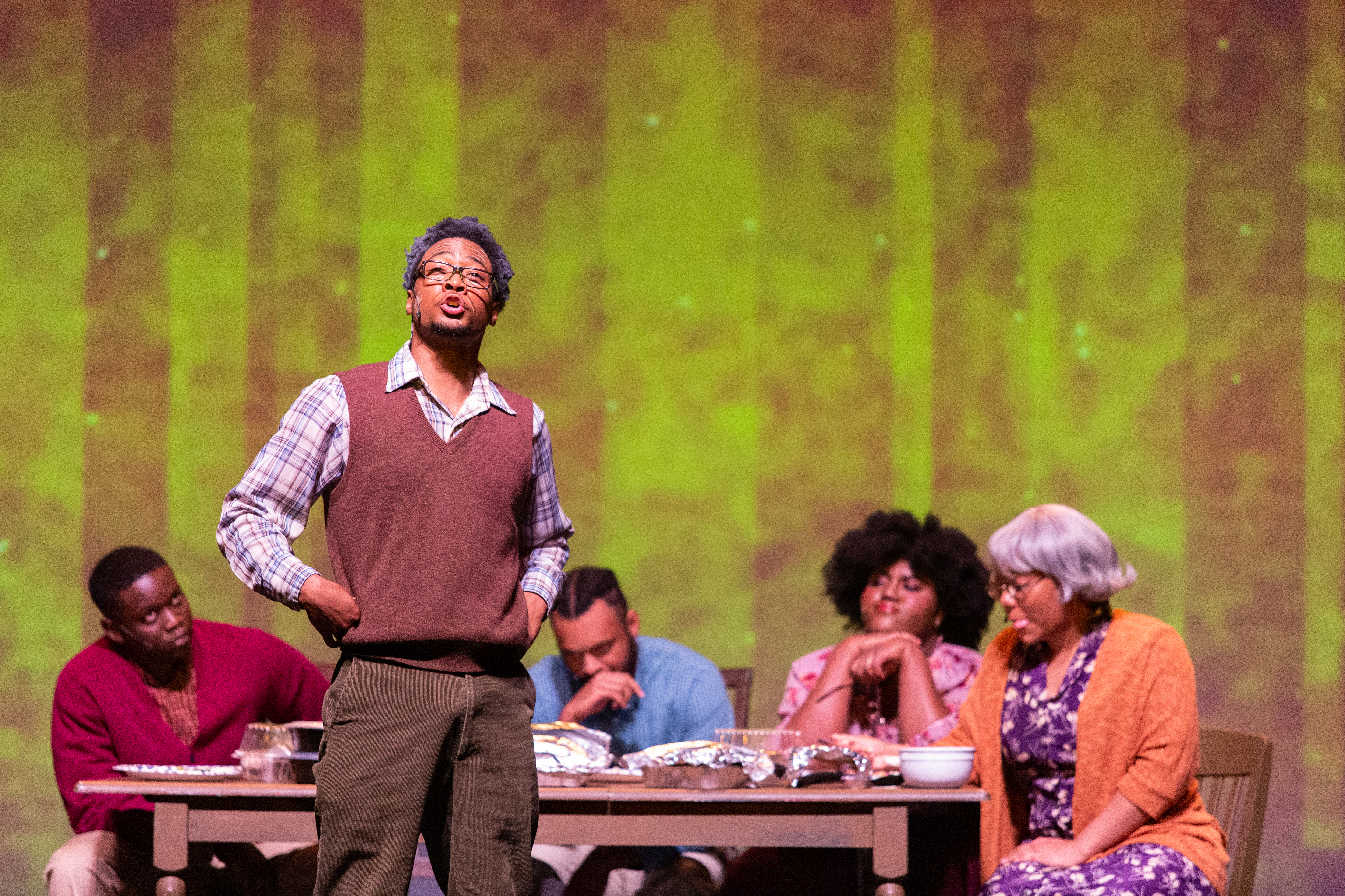 Theatre cast on stage with lead looking into the distance